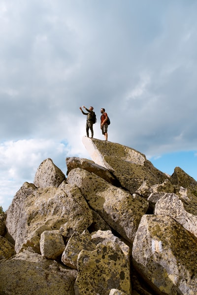 两个人站在白云下的灰色岩石上